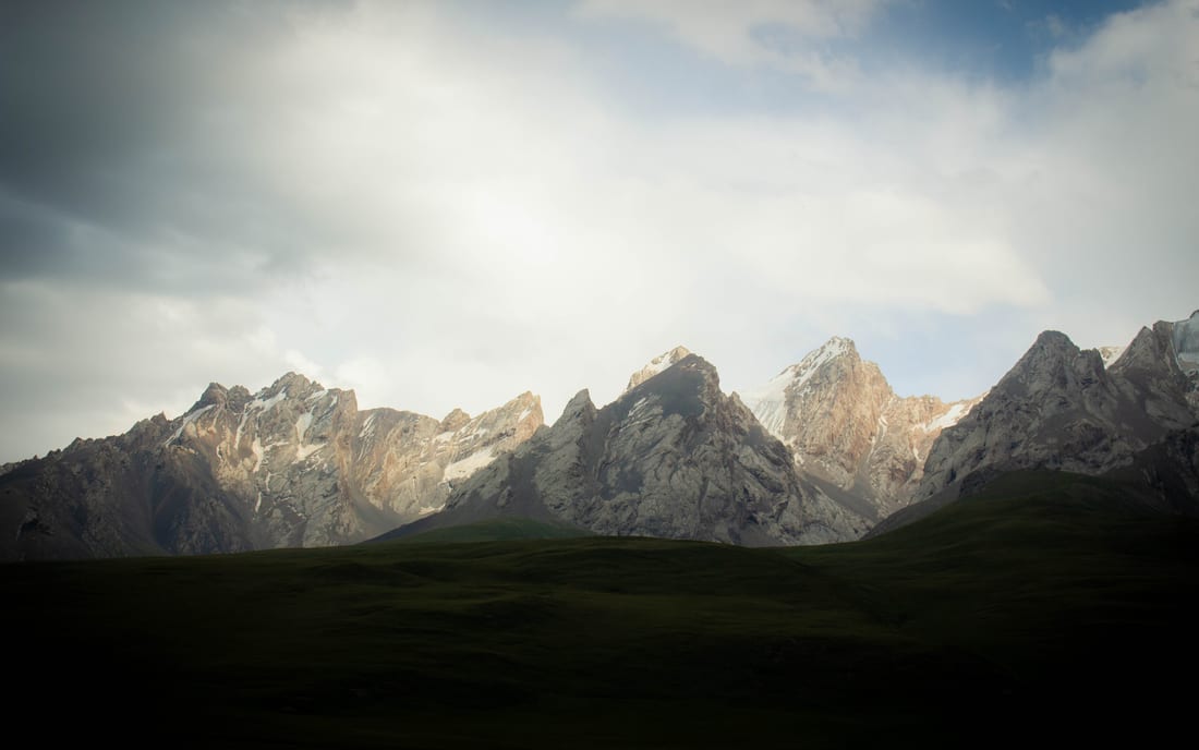Remote misty peaks over an empty green valley