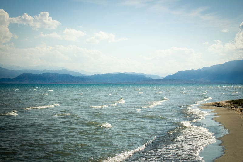 Waves on the sandy shore of Lake Issyk-Kul with the Tian Shan behind