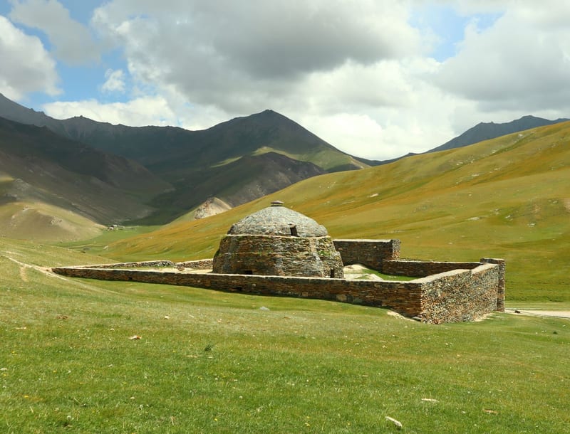 The stone Tash Rabat caravanserai in a green Naryn mountain glen